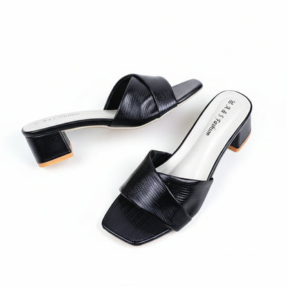 Black open-toe shoes with white soles on a beige background