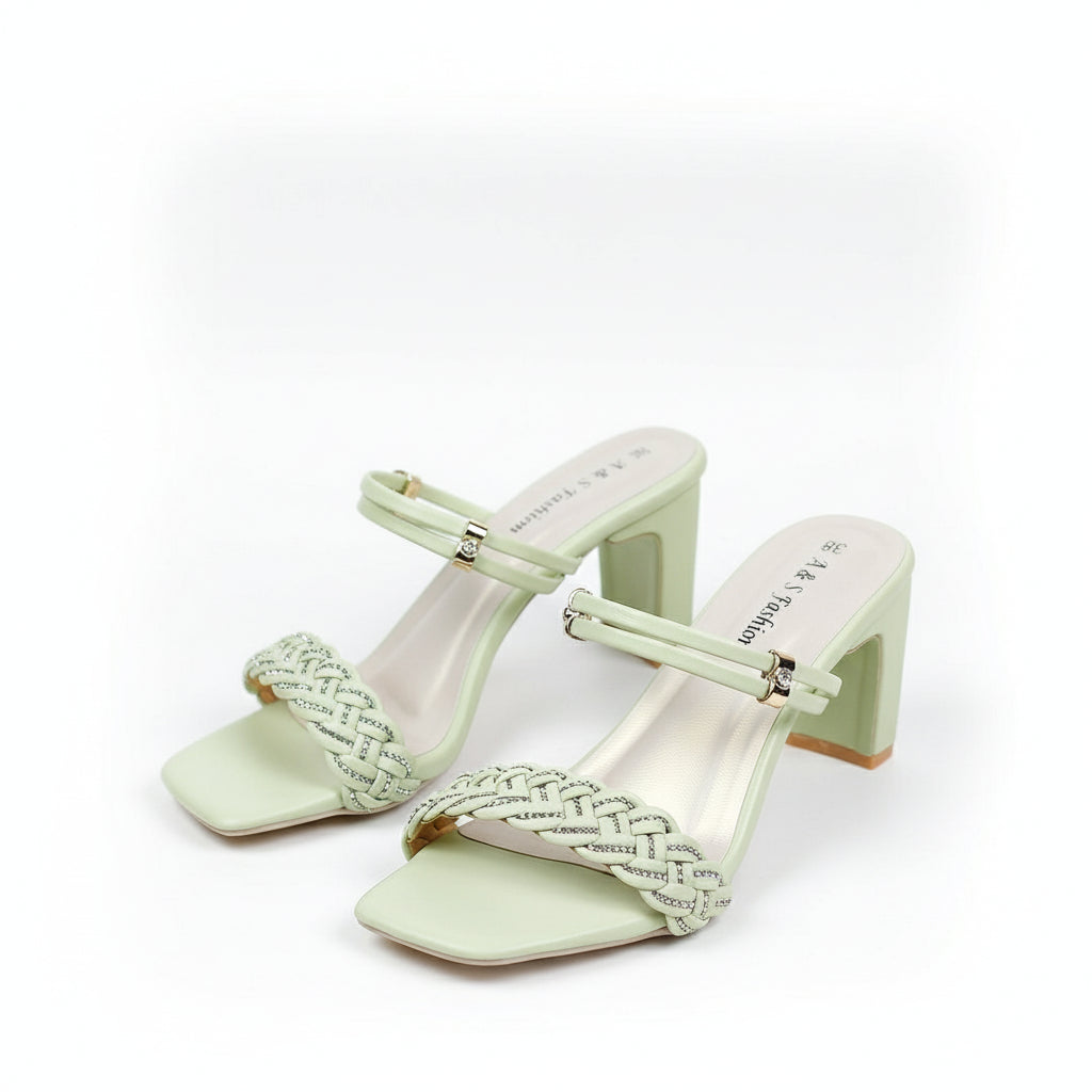 Light green high-heeled shoes with decorative straps on a white surface.